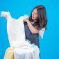 asian maid holding a cloth up from a pile of clean laundry